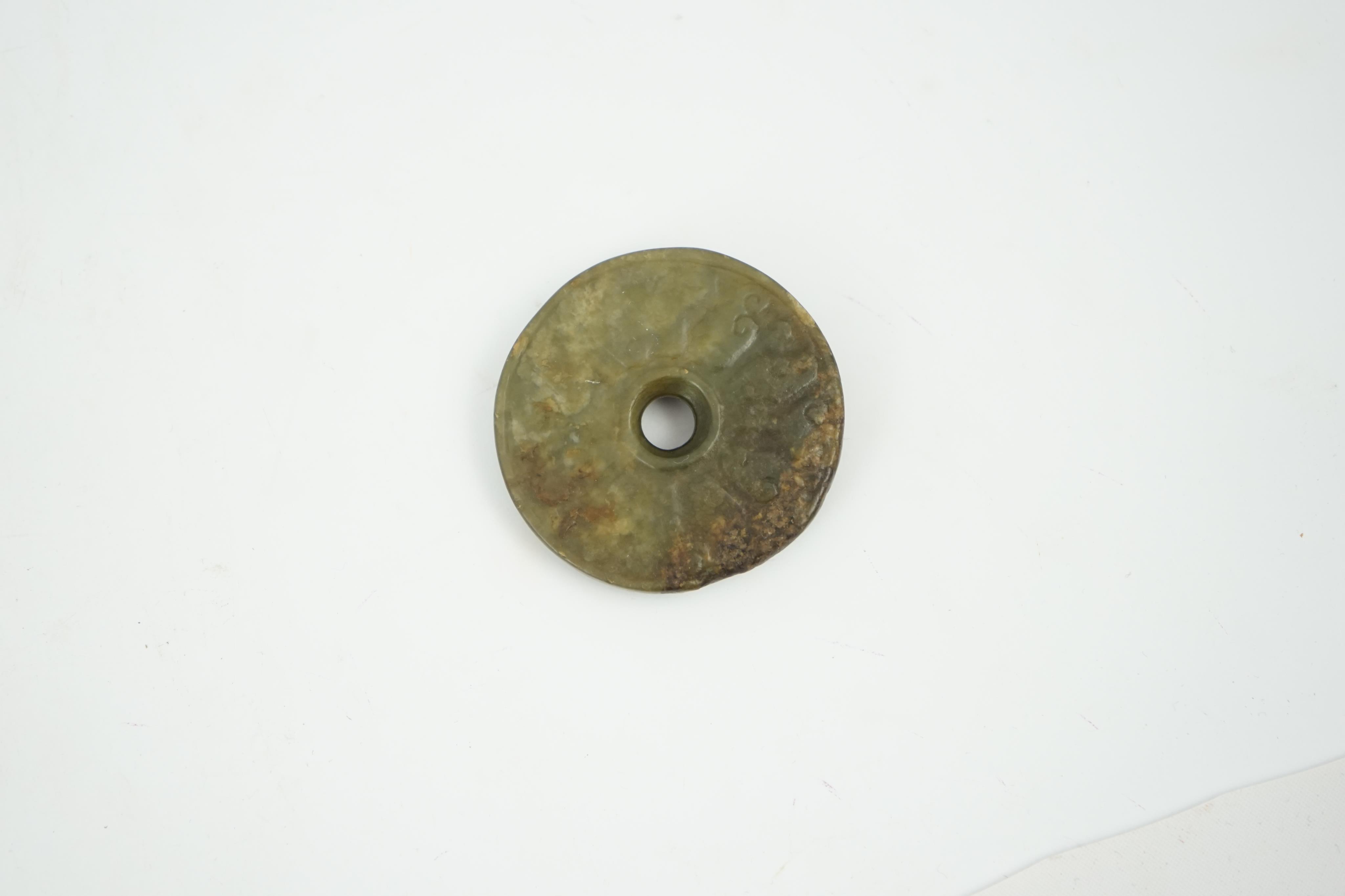 A Chinese green and brown jade bi disc, Yuan/Ming dynasty